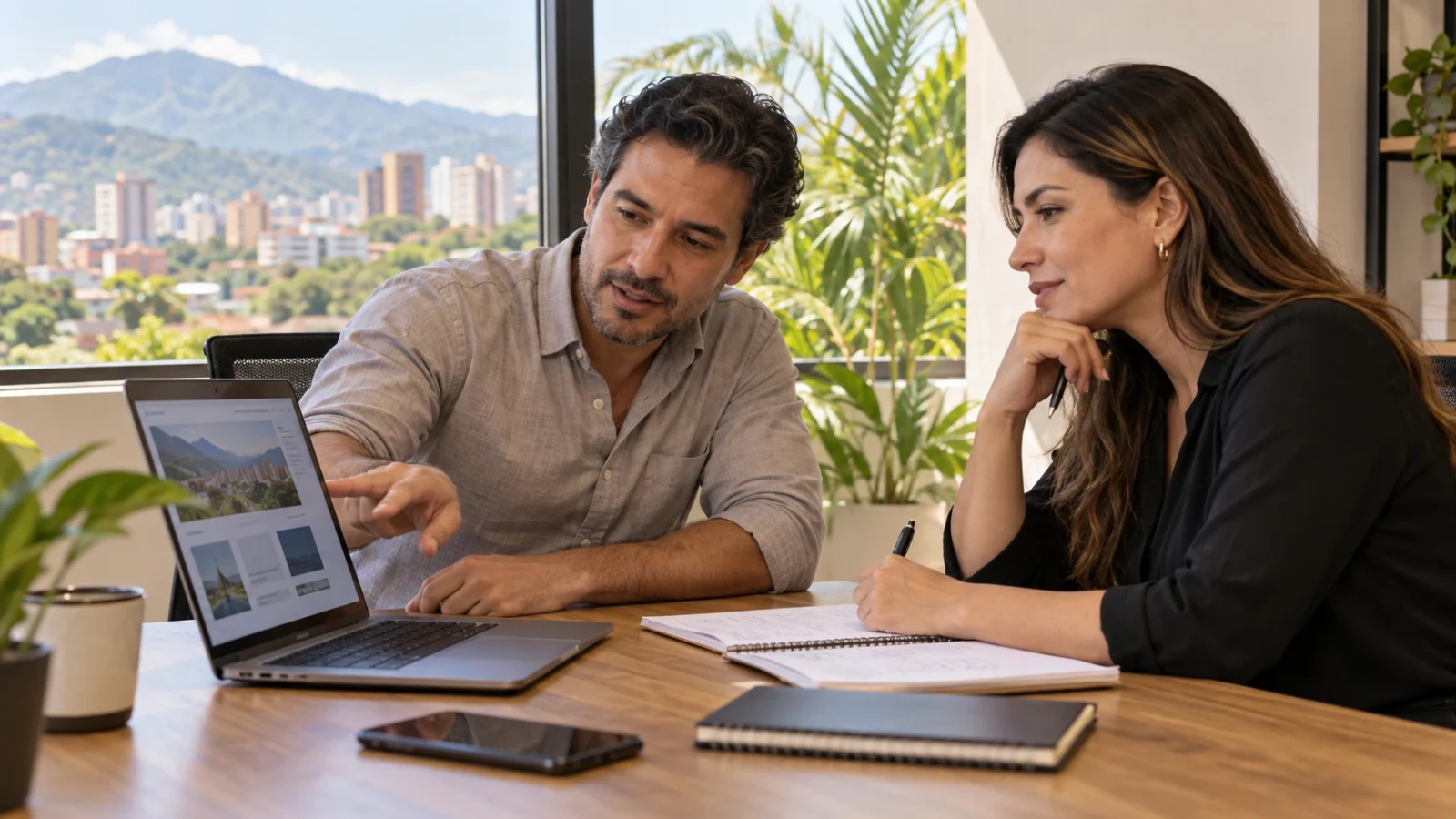 Dos profesionales revisando una página web en un portátil y tomando notas durante una reunión de diagnóstico digital en una oficina luminosa.
